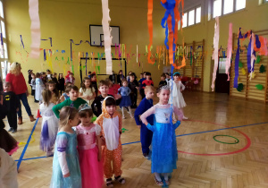 dzieci tańczą na sali gimnastycznej udekorowanej paskami kolorowej bibuły