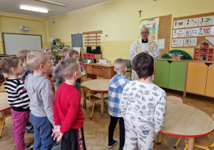 ksiądz modli się z dziećmi w sali