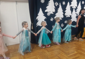 dziewczynki tańczą w kole z nauczycielką