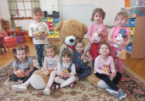 dziewczynki z grupy V pozują do zdjęcia z dużym pluszakiem misia i drobnymi upominkami