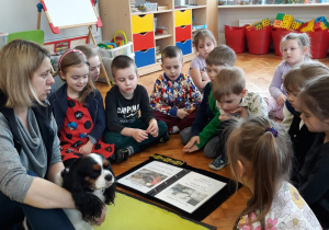 dzieci słuchają opiekunki Molly zgromadzone wokół niej i psa