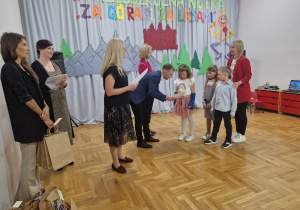nauczycielka wraz z wychowankami z PP Nr 7 "Pod Zielonym Semaforem" w Zduńskiej Woli odbierają nagrody z rąk Przemysława Holewskiego - Zastępcy Biura Edukacji, Sportu i Spraw Społecznych oraz Agnieszki Sapiejki, pani dyrektor Publicznego Przedszkola Nr 10 "Pod Słoneczkiem" w Zduńskiej Woli i Justyny Kunert - zastępcy dyrektora Publicznego Przedszkola Nr 10 "Pod Słoneczkiem"w Zduńskiej Woli a także Jury