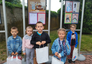 przedszkolaki z nagrodami stoją przed swoimi pracami w Muzeum Historii Miasta w Zduńskiej Woli