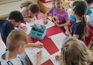 dzieci przy stolikach wykonują ćwiczenia na kartach pracy