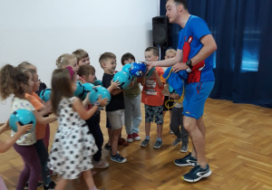 instruktor wita się z dziećmi dotykając się piłkami