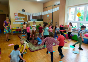 mama Antka prowadzi zabawę z kolorowymi kartkami leżącymi na podłodze