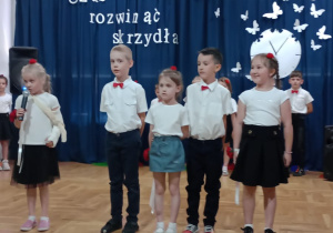 grupa przedszkolaków stoi w szeregu i recytuje wiersz