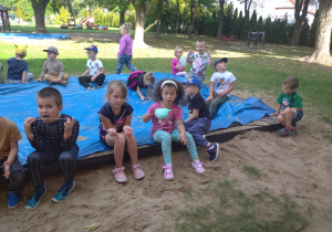 dzieci w ogrodzi jedzą zieloną watę cukrową