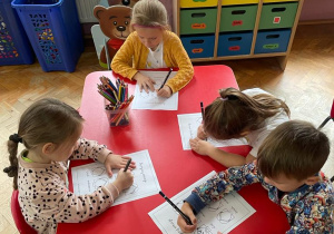 dzieci przy stolikach rysują na twarzach emocje