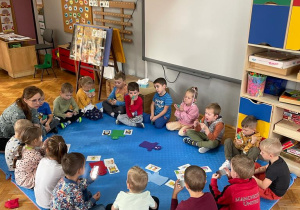 przedszkolaki siedzą w kole z panią psycholog i rozmawiają