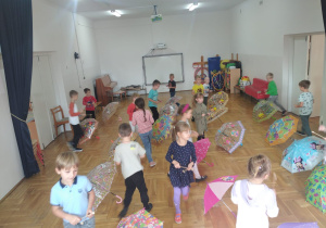 przedszkolaki tańczą wokół parasoli