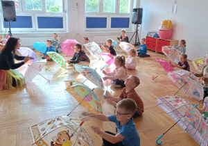 dzieci z panią Nytką grają na rozłożonych parasolkach