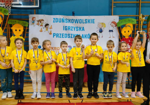 drużyna dzieci z zawieszonymi medalami na szyi i pucharem