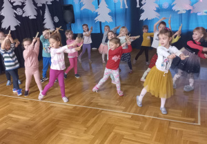 dzieci uderzają drewienkami o siebie z wyciągniętymi ramionami w prawą stronę