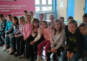 zdjęcie grupowe dzieci siedzących na ławkach przed Jasełką