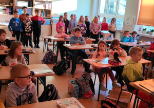 przedszkolaki siedzą w szkolnych ławkach