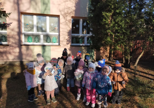 grupa przedszkolaków ze smakołykami dla ptaków przed przedszkolem
