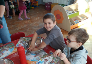 chłopiec ugniata ciasto w misce