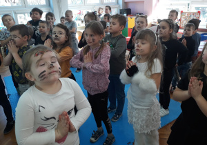 zabawa relaksacyjna "koty medytują" - dzieci stoją w rozsypce ze złączonymi dłońmi i zamkniętymi oczami