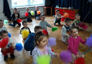 przedszkolaki klęczą i machają pomponami przed sobą