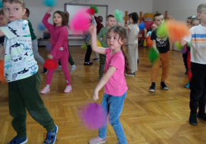 dzieci wymachują kolorowymi pomponami stojąc w szeregach