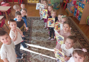 chłopcy stoją na przeciwko dziewczynek po wręczeniu im laurek z kwiatami
