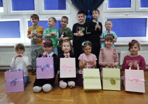 dziewczynki trzymają torebki z upominkami pozując wraz z chłopcami do zdjęcia grupowego
