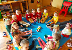 przedszkolaki siedzą w kole i pokazują swoje kolorowe skarpetki