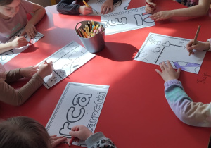 przedszkolaki kolorują kawałki puzzli na stole