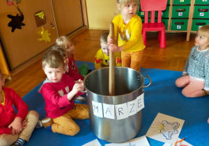 przedszkolaki w dużym garnku mieszają dużą drewnianą łyżką marcową pogodę
