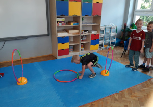 dzieci wykonują ćwiczenie ruchowe z wykorzystaniem kół hula hop