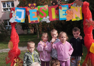 przedszkolaki gr IV pozują do zdjęcia pod ramką z napisem jesień w ogrodzie przedszkolnym