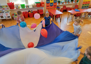 dzieci rzucają balony poruszajac chustą animacyjną