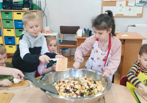 przedszkolaki wrzucają pokrojone owoce z desek do miski