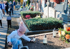 przedszkolaki kładą lampion na grobie lotnika