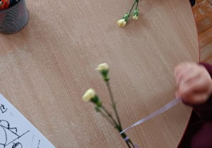 dzieci uczą się wiązać kokardki na kwiatkach
