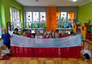 przedszkolaki trzymają dużą flagę Polski