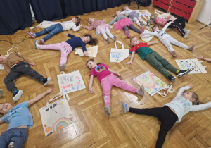 podczas relaksu przedszkolaki leżą na podłodze obok swoich torebek