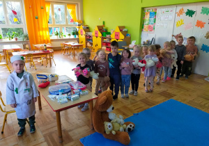 przedszkolaki stoją w kolejce do lekarza ze swoimi misiami