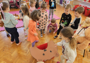 dzieci karmią misia wrzucając do jego paszczy kulki