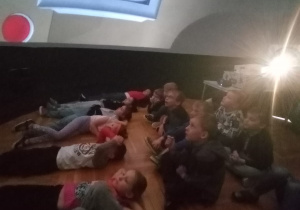 dzieci siedzą lub leżą oglądając film