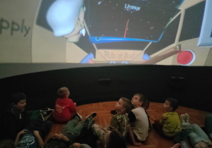 dzieci siedzą lub leżą oglądając film
