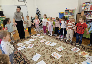 dzieci z panią psycholog stoją w kole trzymając się za ręce i przekazują sobie iskierkę