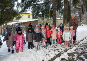 przedszkolaki z nauczycielką w ogrodzie przedszkolnym stoją przy karmniku