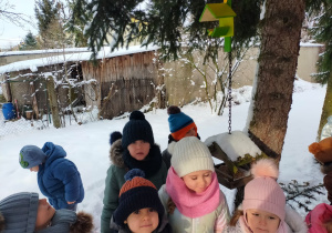 w ogrodzie dzieci stoją przy karmniku