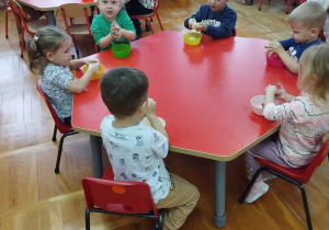 przedszkolaki ugniatają masę w miseczkach siedząc przy stoliku