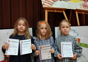 trzy dziewczynki biorące udział w konkursie z dyplomami