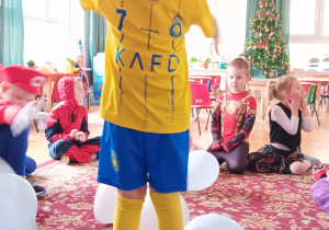 chłopiec prezentuje dzieciom swój kostium piłkarza stojąc wśród balonów