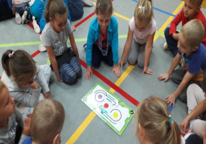 dzieci patrzą na poruszające się po drodze zaprogramowanego robota