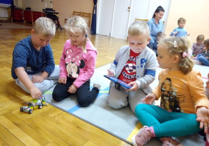 dzieci siedzą na podłodze i kodują na tablecie
